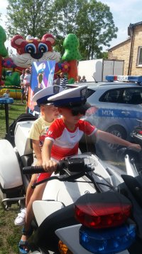 Fotografia kolorowa przedstawiająca dzieci siedzące na motocyklu policyjnym