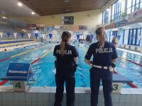 fotografia kolorowa przedstawiająca policjantki obserwujące pływające dzieci podczas turnieju