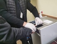 Fotografia kolorowa przedstawiająca mement pobierania odcisków palców od osoby zatrzymanej