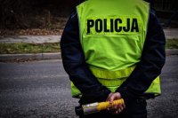 policjant &quot; drogówki&quot; w żółtej kamizelce, trzymający alkomat w dłoniach