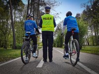 policjantka ruchu drogowego raz z 2 rowerzystami ubranymi w stroje sportowe.