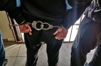 policjanci wraz z zatrzymanym mężczyzną, który ma założone kajdanki