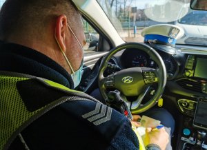 widok zza ramienia policjanta drogówki, który zapisuje przebieg kontroli w notatniku służbowym