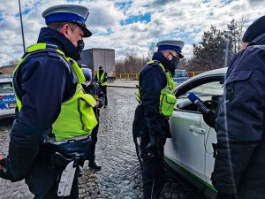 dwóch policjantów białostockiej drogówki, którzy stoją przy kontrolowanym srebrnym pojeździe