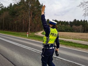 policjantka ruchu drogowego z podniesiona lewą dłonią, która nakazuje pojazdowi zatrzymanie się do kontroli